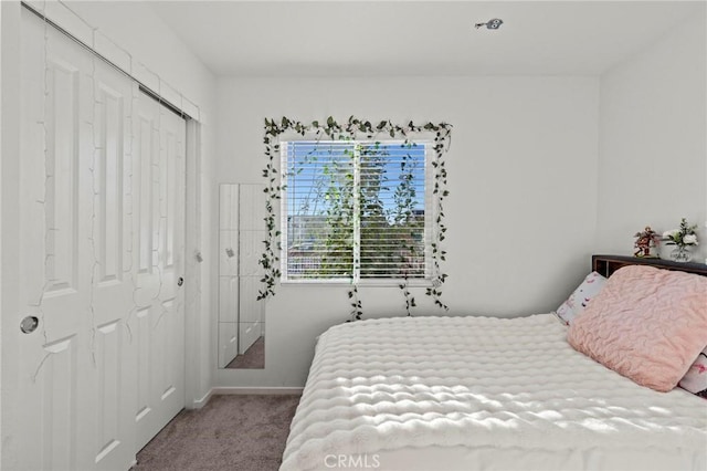 carpeted bedroom with a closet and baseboards