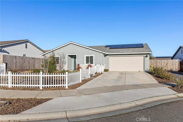 single story home featuring a garage, concrete driveway, a fenced front yard, and solar panels