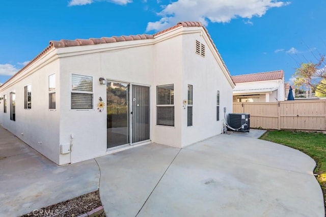 back of house with central air condition unit, stucco siding, a patio, and fence