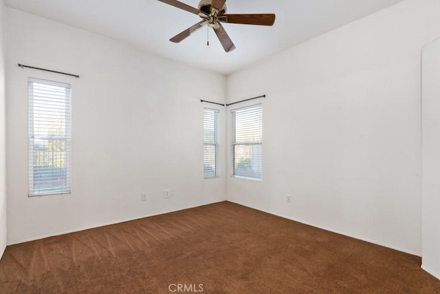 unfurnished room with ceiling fan and dark carpet