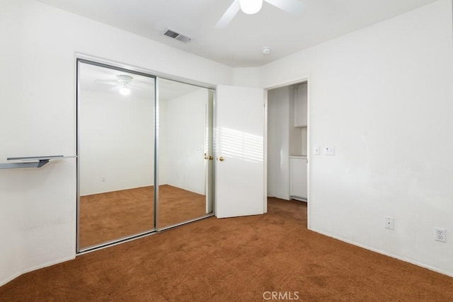 unfurnished bedroom with a closet, carpet flooring, visible vents, and a ceiling fan