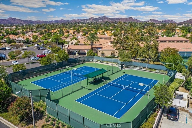 view of tennis court with a residential view, fence, and a mountain view