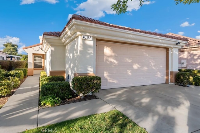 view of front of house with an attached garage, stucco siding, driveway, and a tiled roof