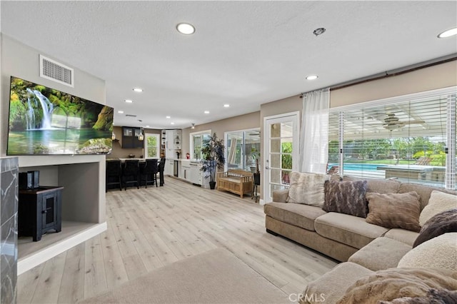 living room with light wood-type flooring, visible vents, and recessed lighting