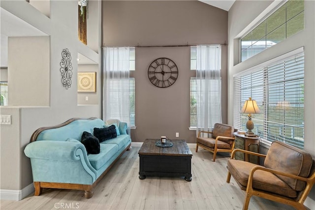 living room with high vaulted ceiling, baseboards, and wood finished floors