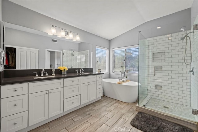 bathroom featuring a shower stall, visible vents, vaulted ceiling, and a sink