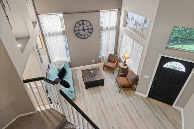 entryway with a high ceiling, stairway, wood finished floors, and baseboards