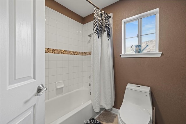 full bath with toilet, shower / tub combo, and a textured wall