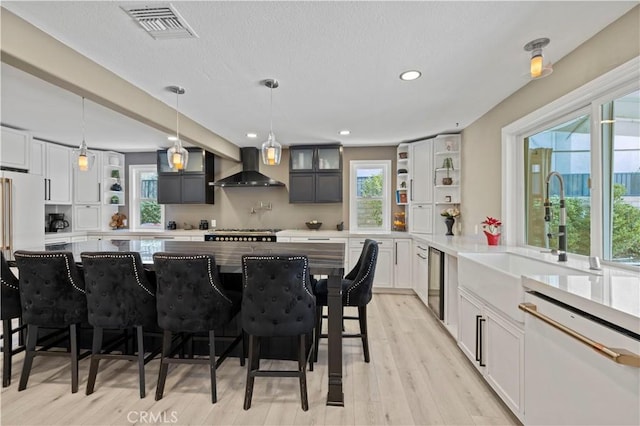 kitchen featuring open shelves, visible vents, a sink, white appliances, and wall chimney exhaust hood