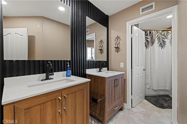 full bathroom with marble finish floor, visible vents, two vanities, and a sink