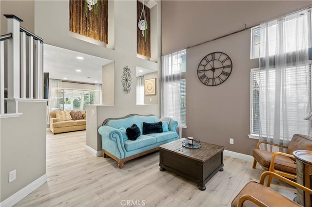 living area featuring a high ceiling, wood finished floors, and baseboards