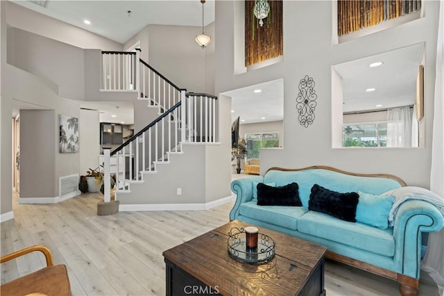 living area featuring a wealth of natural light, visible vents, baseboards, and wood finished floors