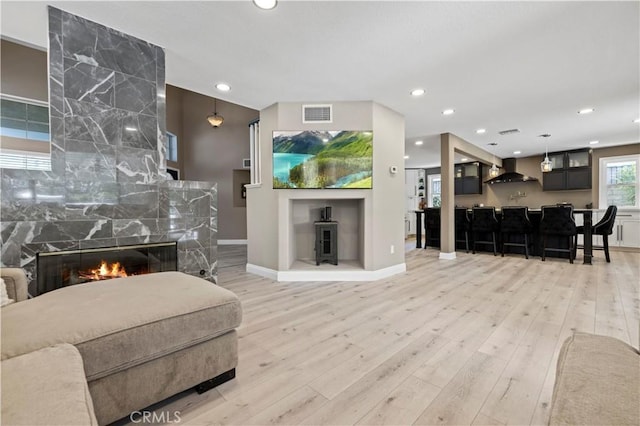 living area with recessed lighting, indoor bar, wood finished floors, visible vents, and a high end fireplace