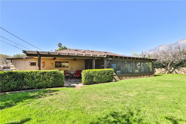 back of house with a lawn, a ceiling fan, a patio, a sunroom, and stucco siding