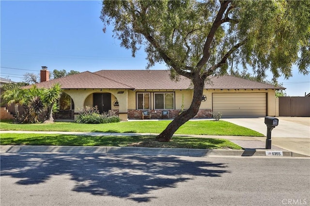 single story home with a garage, a front yard, concrete driveway, and stucco siding