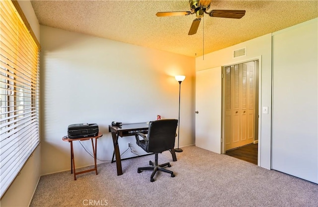 carpeted home office with visible vents, ceiling fan, and a textured ceiling