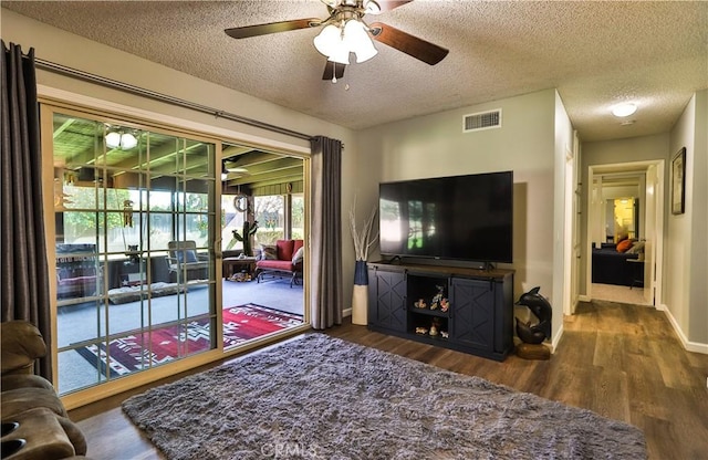 living area with visible vents, a textured ceiling, baseboards, and wood finished floors