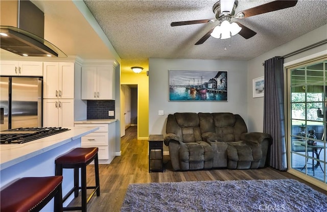 living area featuring dark wood-type flooring, ceiling fan, a textured ceiling, and baseboards