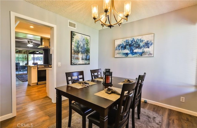 dining area featuring baseboards, a textured ceiling, visible vents, and wood finished floors