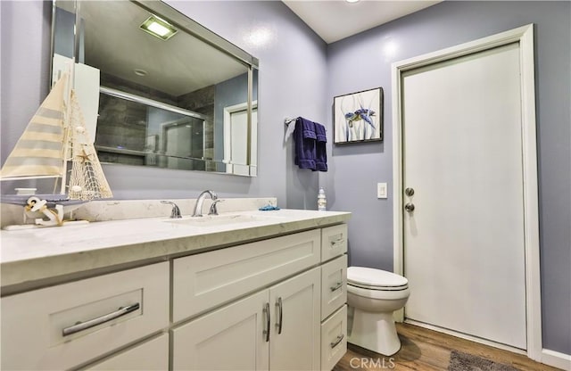 full bath featuring toilet, a stall shower, wood finished floors, and vanity