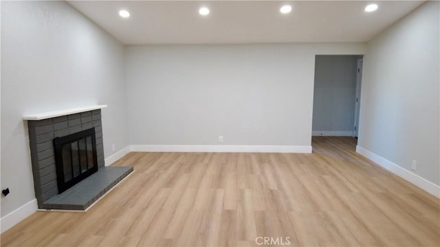 unfurnished living room with light wood finished floors, a fireplace, recessed lighting, and baseboards