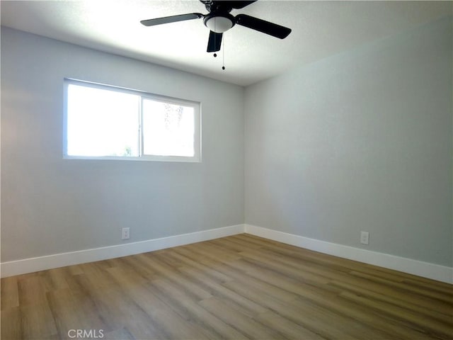 spare room featuring ceiling fan, wood finished floors, and baseboards