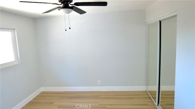 unfurnished bedroom with light wood-style floors, a closet, ceiling fan, and baseboards