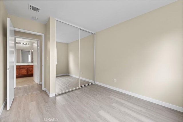 unfurnished bedroom with light wood finished floors, a closet, visible vents, and baseboards