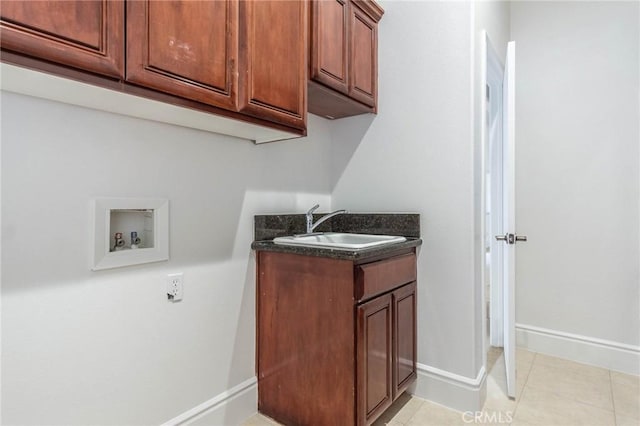 washroom featuring light tile patterned flooring, washer hookup, a sink, baseboards, and cabinet space