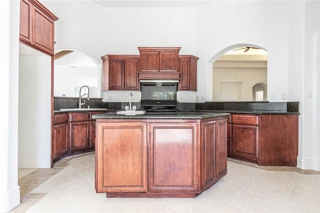 kitchen featuring light tile patterned floors, a high ceiling, a sink, and a center island