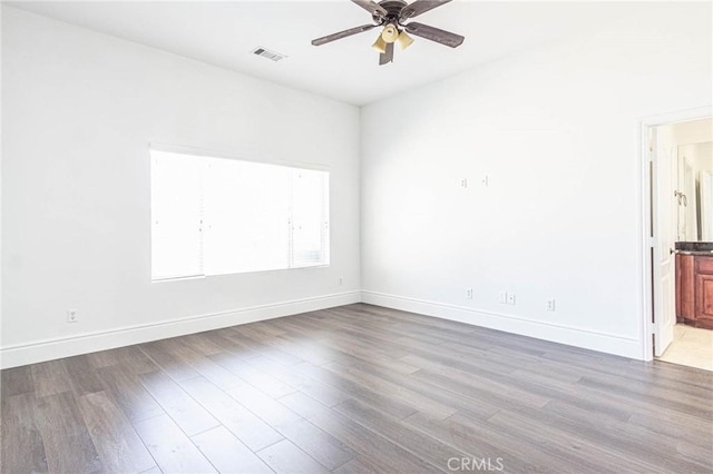 empty room featuring baseboards, wood finished floors, visible vents, and a ceiling fan