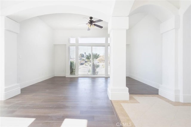 empty room with decorative columns, baseboards, and a ceiling fan