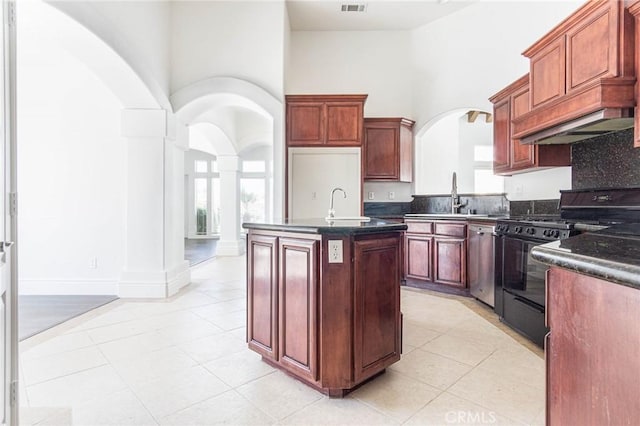 kitchen with arched walkways, a towering ceiling, stainless steel dishwasher, dark countertops, and black gas range oven