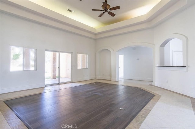 interior space featuring a high ceiling, a ceiling fan, visible vents, and baseboards