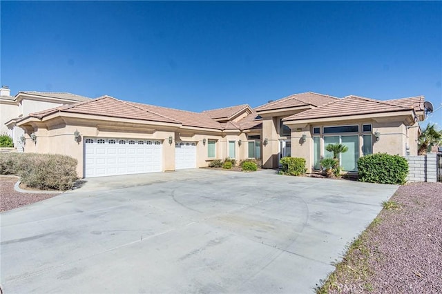 prairie-style home featuring a garage, fence, a tile roof, driveway, and stucco siding