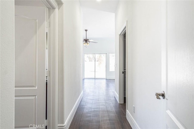 corridor with baseboards and dark wood finished floors