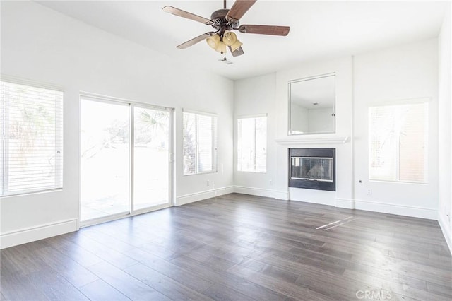 unfurnished living room with a glass covered fireplace, wood finished floors, and baseboards