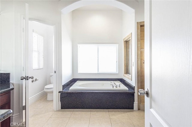 bathroom with toilet, a garden tub, tile patterned flooring, and vanity