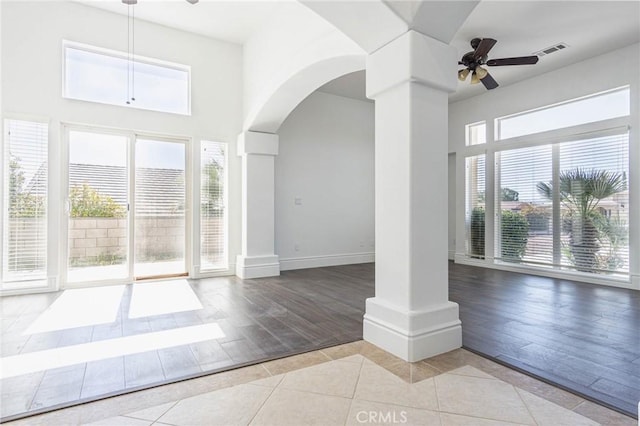 unfurnished living room with visible vents, ceiling fan, decorative columns, and tile patterned floors