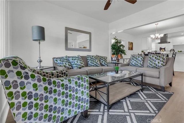 living area with wood finished floors and ceiling fan with notable chandelier