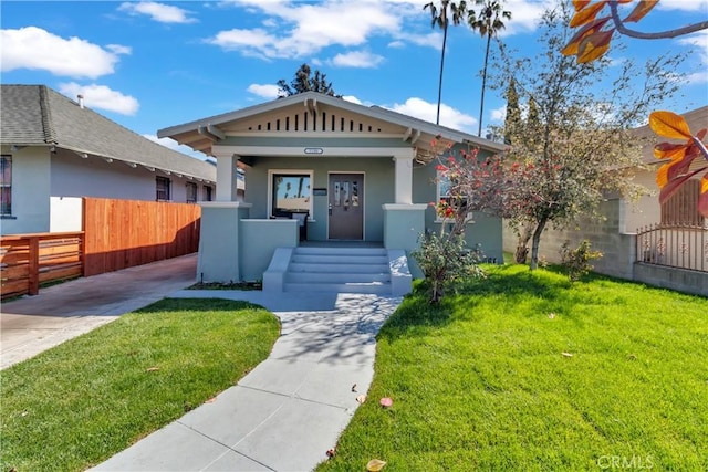 view of front of property featuring a front yard, a porch, fence, and stucco siding