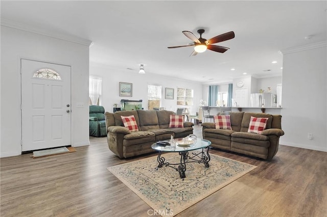 living room featuring a ceiling fan, baseboards, ornamental molding, and wood finished floors