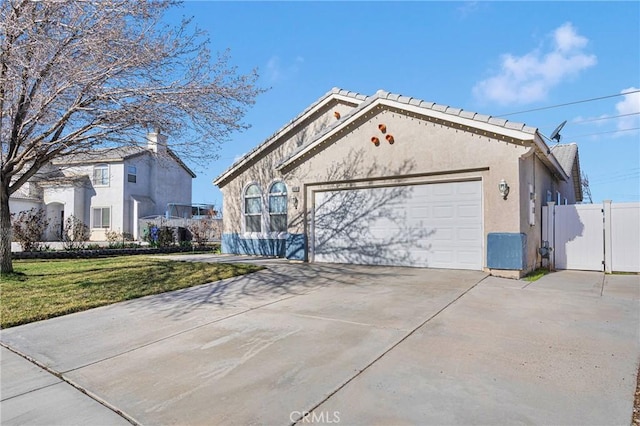 view of front of house with a garage, concrete driveway, a gate, a front lawn, and stucco siding