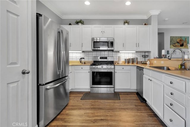 kitchen featuring appliances with stainless steel finishes, white cabinetry, a sink, and ornamental molding