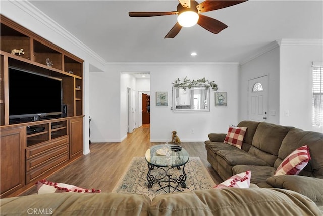 living area with ornamental molding, light wood-type flooring, ceiling fan, and baseboards