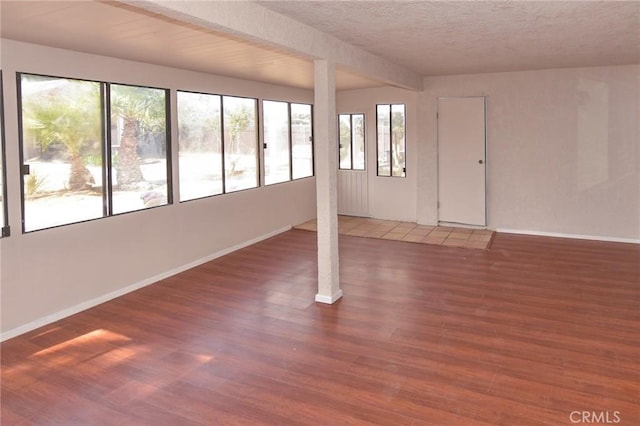 interior space with a textured ceiling, baseboards, and wood finished floors