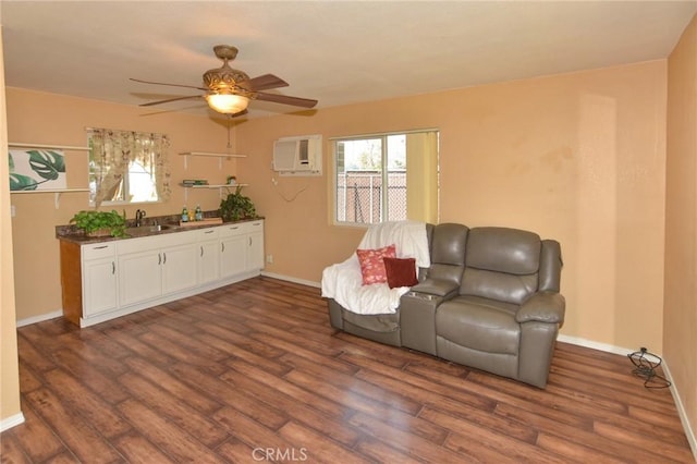 living area featuring dark wood-type flooring, a wall mounted air conditioner, and baseboards