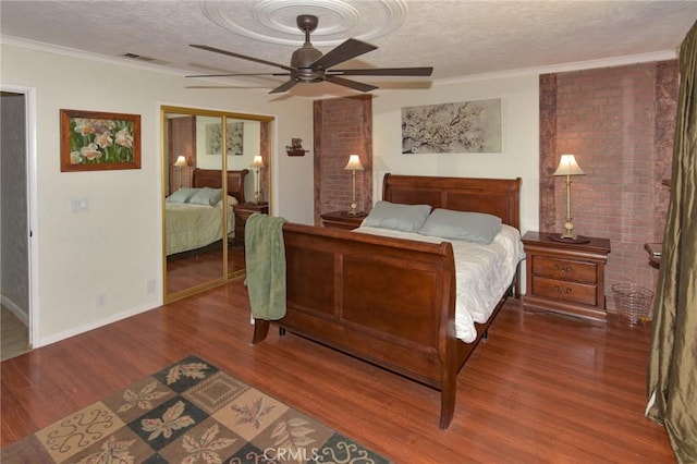 bedroom featuring a closet, visible vents, ceiling fan, a textured ceiling, and wood finished floors