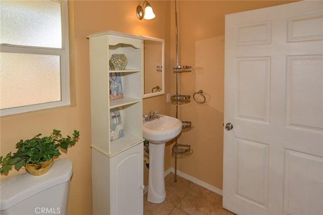 half bathroom featuring baseboards, a sink, toilet, and tile patterned floors