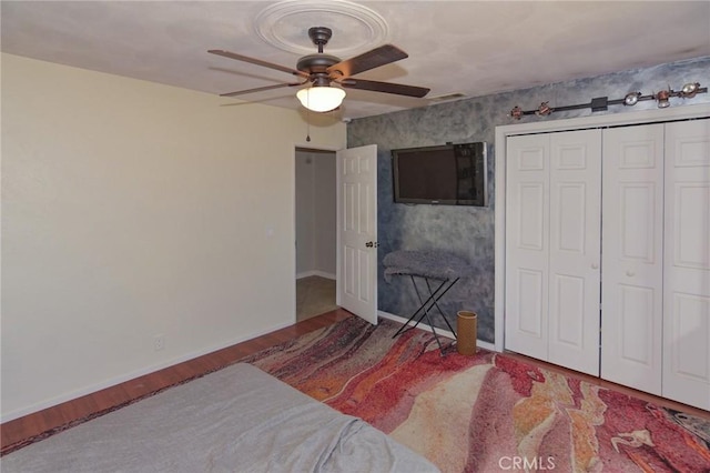 bedroom featuring a ceiling fan, a closet, baseboards, and wood finished floors